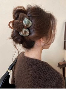 Detail view of brown plush hair claw clip with bow on dark hair for autumn styling