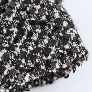Detailed macro view of black and white tweed fabric texture with black sequin embellishments