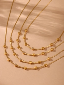 Detail of multi-layer 18K gold-plated herringbone necklaces with heart-shaped zircon charms
