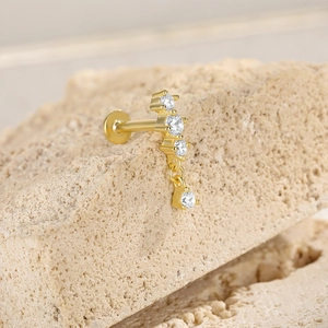 Macro detail of a gold S925 silver butterfly earring with four clear stones on a stone base