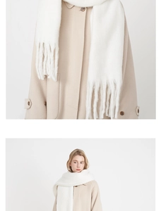 Detail of white pashmina-style scarf texture with long fringe on a beige coat