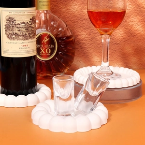 Detailed view of bubble wave coasters holding wine bottles and glasses on a warm surface