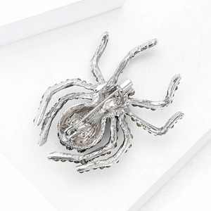 Detail of silver spider brooch with dark gemstones and functional pin back closure