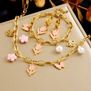 Detailed shot of a gold jewelry set featuring pink tulip, bee, and flower charms with pearls