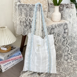 Détail du sac en toile texturée à fleurs avec bandoulière à volants bleu clair