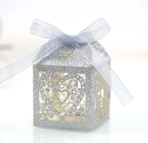Détail macro du motif cœur découpé au laser sur boîte à bonbons argentée pailletée