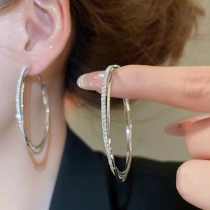 Detailed view of silver double-layered intertwined hoop earrings with inlaid zircons