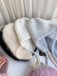 Flach liegende bunte Angora-Strickmützen mit Ohrenklappen und Quasten für den Winter
