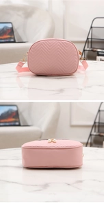 Detail of pink V-quilted faux leather bag with pearl zipper on marble surface