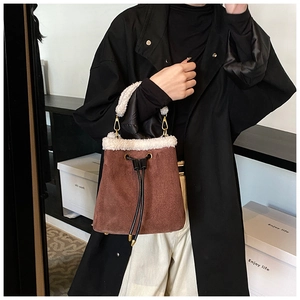 Detailed shot of brown suede bucket bag with plush white faux fur trim and drawstrings