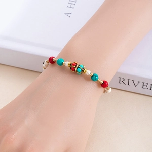 Gros plan d'un bracelet ethnique perlé avec turquoise et cloches porté au poignet