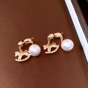 Detailed view of vintage gold horse earrings with pearls on dark textured background
