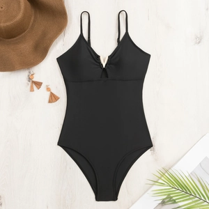 Flat lay of black one-piece swimsuit with V-neck gold hardware and summer accessories