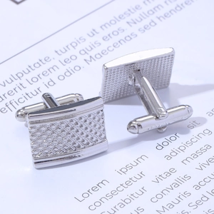 Macro shot of silver square cufflinks featuring intricate engraved stripe metal textures