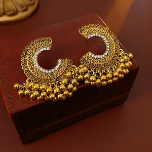 Dettaglio macro di orecchini vintage dorati con strass e nappe di perline