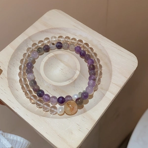 Detail of amethyst beaded bracelet with citrine stone on a natural wooden display stand