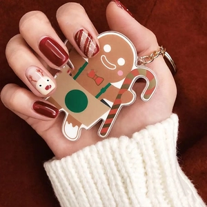 Christmas gingerbread man keychain held by hand with holiday reindeer nail art