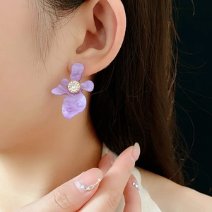 Détail de la boucle d'oreille fleur en résine violette avec zircon porté