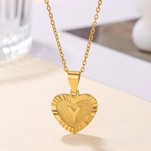 Macro shot of gold heart pendant with letter Y and sunburst radiant texture