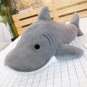 Detail of blue shark plush toy with soft grey fabric and red star embroidery on bed