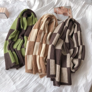 Detailed knit texture of green, brown and beige checkerboard scarves on fabric