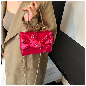 Detail of fuchsia satin evening clutch with rhinestones and beaded handle in hand