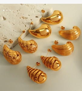 Detailed macro view of four pairs of 18k gold-plated titanium steel earrings with varied textures
