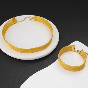 Détail d'un ensemble collier choker et bracelet en maille dorée sur support moderne