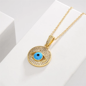 Macro shot of gold evil eye pendant necklace with blue eye and pavé zircon stones