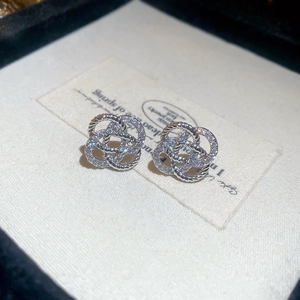 Détail de boucles d'oreilles fleurs en argent avec zircons et design torsadé