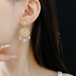 Detail of dreamcatcher style earrings with pink bead fringe on a model's ear