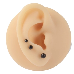 Trois tailles de boucles d'oreilles boules noires en acier sur un modèle en silicone