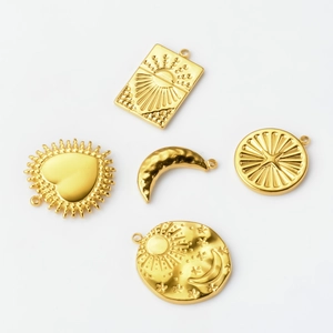 Detail of five gold stainless steel pendants with celestial sun moon and star motifs