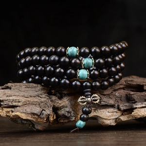 Gros plan de 108 perles de prière en bois de santal noir avec accents turquoise sur bois