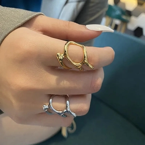 Detailed close-up of gold and silver irregular liquid-style rings on hand