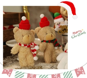 Close-up of a plush Christmas bear doll with a red knit hat and a striped scarf decoration