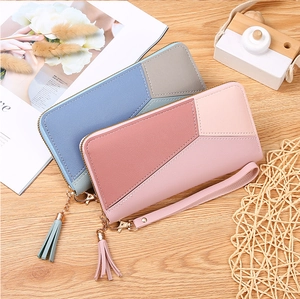Detailed view of color-block long wallets with tassel and wristlet on wooden texture