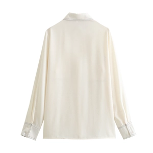 Back view of minimalist cream long sleeve blouse with black contrast stitching detail