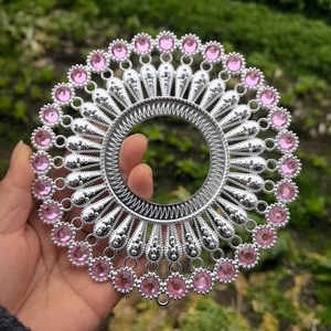 Close-up of silver metal wall decor with pink rhinestones and hollow center design