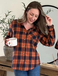 Close-up of orange and black plaid shirt detailing button collar and single chest pocket