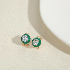 Detail of green enamel round earrings with sparkling zircon center and gold finish
