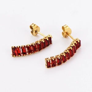 Detail view of golden curved earrings featuring rectangular red zircon stones on white background