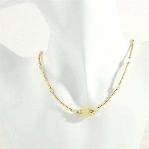 Close-up of beaded necklace with gold metal beads and translucent light green stones