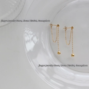 Detailed view of elegant gold tassel chain earrings with smooth spherical metal studs