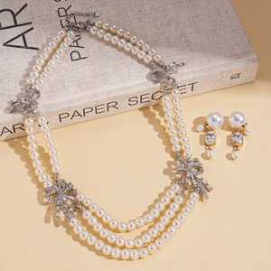 Elegant multi-layer pearl necklace and earring set with rhinestone bow details