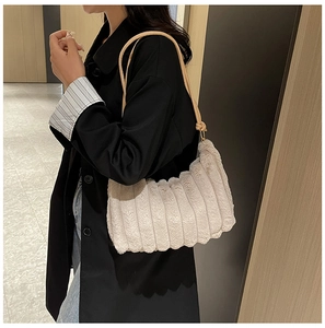 Modella che indossa una borsa sottobraccio beige in peluche a coste con tracolla sottile
