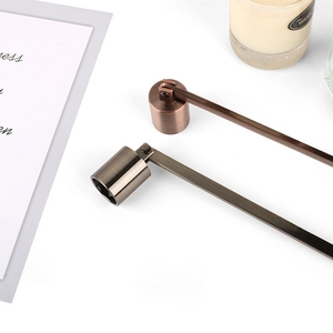 Polished stainless steel candle snuffers in bronze and grey on a white tabletop
