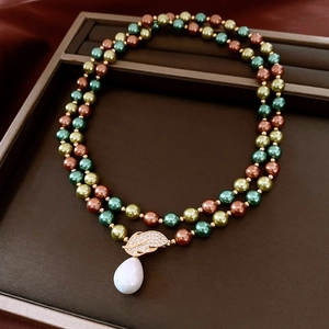 Detail of vintage 18K gold plated necklace with colorful pearls and leaf pendant