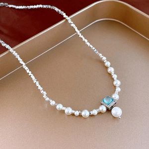 Détail d'un collier de perles plaqué or 18k avec pierre bleue carrée et perle pendante
