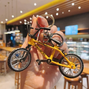 Close-up of a yellow miniature mountain bike keychain with a realistic metal ring